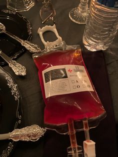 an assortment of silverware and wine glasses on a black table cloth with red liquid in it