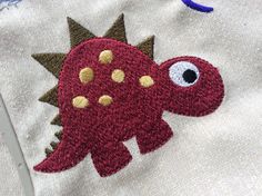 a close up of a piece of cloth with a dinosaur embroidered on the front and back