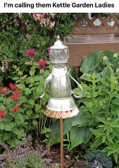 a metal lamp sitting on top of a wooden pole next to flowers and plants in a garden