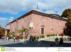 people are walking around in front of an old brick building with two domes on top