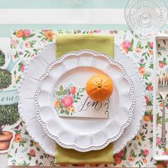 an orange sitting on top of a white plate next to a fork and spoons