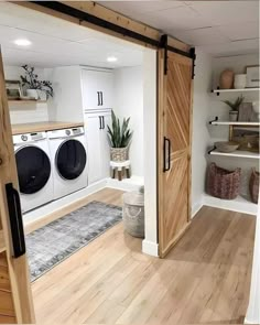 a washer and dryer in a room with wooden floors, white walls and open doors