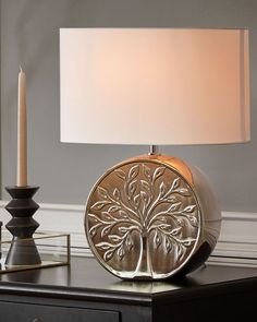 a table lamp sitting on top of a night stand next to a candle and vase