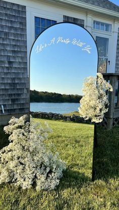 a mirror sitting on top of a grass covered field next to a tree and building