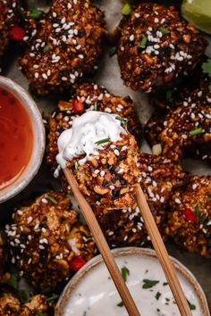 a wooden spoon with some food on top of it and dipping sauce in the bowl