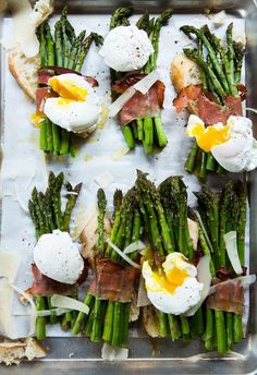 asparagus, eggs and prosciutto arranged on a baking sheet