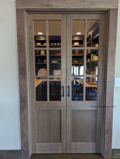 two wooden doors with glass inserts on each side and shelves in the middle, against a white wall