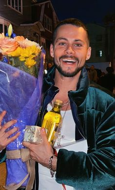 a man holding a bouquet of flowers and a bottle