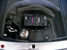 the inside of a car with its hood open and some electrical components in the trunk