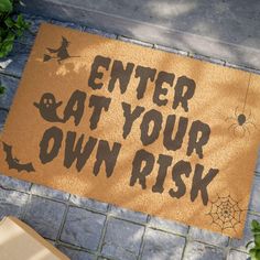 a door mat that says enter at your own risk on the ground next to a plant