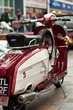 a red and white scooter is parked on the sidewalk