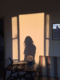 the shadow of a woman's head on a wall next to a striped chair