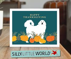 a thanksgiving card with a white dog and pumpkins on the table next to it