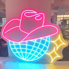 a neon sign in the shape of a cowboy's hat on top of a globe