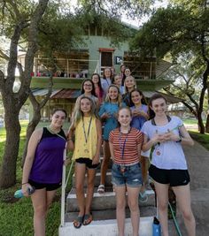 a group of young women standing next to each other in front of a tree house