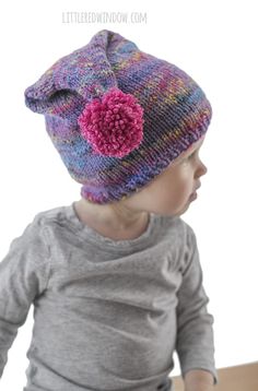 a small child wearing a knitted hat with a flower on the front and side