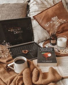 an open laptop computer sitting on top of a bed next to a cup of coffee