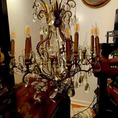 a chandelier hanging from the ceiling in a room with a mirror and clock on the wall