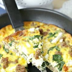 a pizza with sausage, spinach and feta cheese in a cast iron skillet