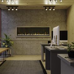 an office with a fireplace and desks in front of the wall is lit by recessed lights