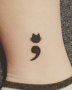 a small black cat tattoo on the ankle