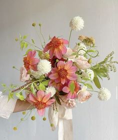 a woman holding a bouquet of flowers in her hand with white and pink colors on it