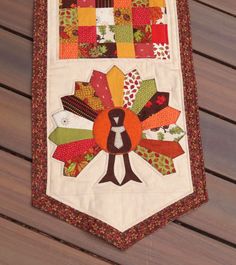 a quilted table runner with an orange and brown turkey on it's side