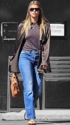 a woman walking down the street wearing jeans