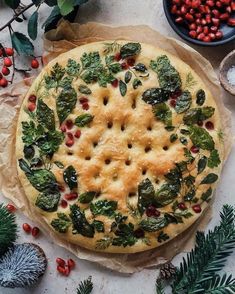 a pie with spinach and cranberries on it sitting next to other christmas decorations