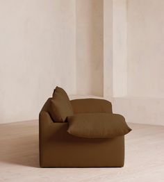 a brown couch sitting on top of a hard wood floor next to a white wall