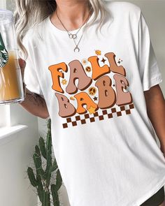 Fall Season is upon us and this cute fall babe shirt will get you in the mood! The retro design is super cute and unqiue, everyone will be obsessed and asking where you got your shirt.  THE MATERIAL: Classic unisex jersey short sleeve tee fits like a well-loved favorite.  Soft cotton and quality print.  The shoulders have taping for better fit over time.  Dual side seams hold the garment's shape for longer. 100% Airlume combed and ringspun cotton (fiber content may vary for different colors) Runs true to size Sizing: Unisex sizing (Looser fit for women) If you're looking for more of a tighter fit size down, oversize fit size up. We do not issue refunds or accept returns due to incorrect sizing, so please double-check the size before purchase. *The placement of the graphic may vary slightly Vintage Slogan T-shirt For Fall, Cute White Fall Shirt, Cute White Shirt For Fall, White Tops With Funny Text For Fall, Retro Graphic Print Tops For Fall, Fun Fall Top With Letter Print, Trendy Fall Slogan Tops, Trendy Fall Shirt With Text Print, Retro Tops With Funny Print For Fall