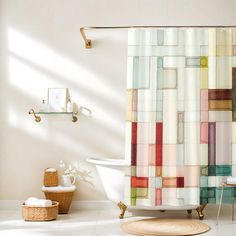 a white bath tub sitting next to a shower curtain covered in multicolored tiles