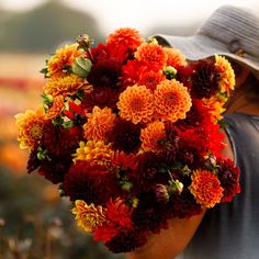 a man holding a bouquet of flowers in his hand and wearing a hat on his head