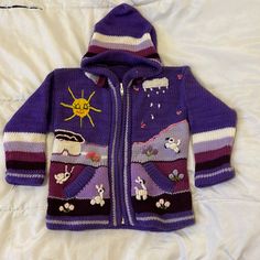 a child's purple jacket with pictures on the front and back, sitting on a bed