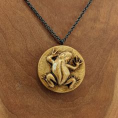 a wooden pendant with a frog on it