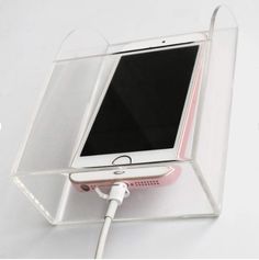 an iphone is plugged into a charger in a clear plastic box with the cord attached