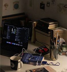 an open laptop computer sitting on top of a desk next to books and other items