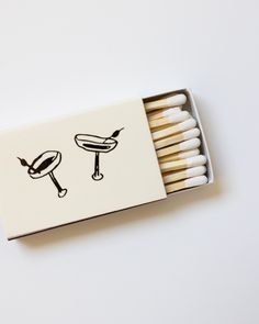 matches are arranged in a matchbox on a white surface, with the image of a grill and hot dog