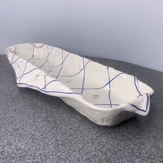 a white and blue bowl sitting on top of a gray counter next to a wall