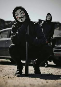 two people in masks are sitting on the ground with their faces painted black and white