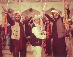 men in traditional garb and turbans holding up their hands at an event