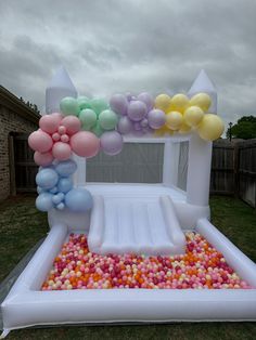 an inflatable arch with balloons and streamers on the ground for a birthday party