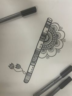 a pen and some markers on top of a piece of paper with an intricate design