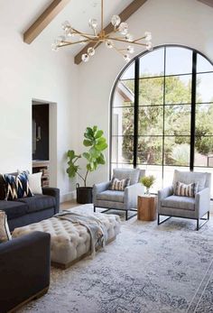 a living room with couches, chairs and a rug in front of a large window