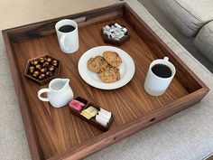 a tray with coffee, cookies and other snacks on it next to two mugs