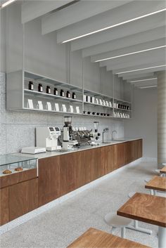 an empty restaurant with wooden tables and white counter tops, along with lots of shelves