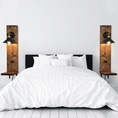 a bed with white sheets and pillows next to two wooden speakers on the wall above it