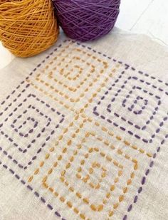 two balls of yarn sitting next to each other on top of a white tablecloth