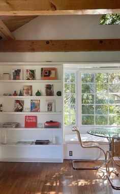 a living room filled with furniture and bookshelves next to a wooden floor covered in windows