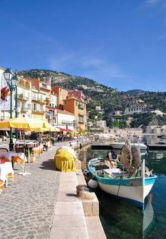 a boat is docked in the water next to some buildings and tables with umbrellas